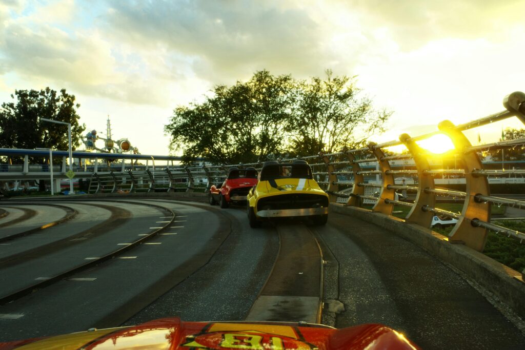 Capture the thrill of a theme park car ride under a vibrant sunset.