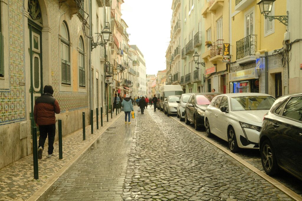 Charming cobblestone street in Lisbon with people strolling and colorful buildings lining the pathway.