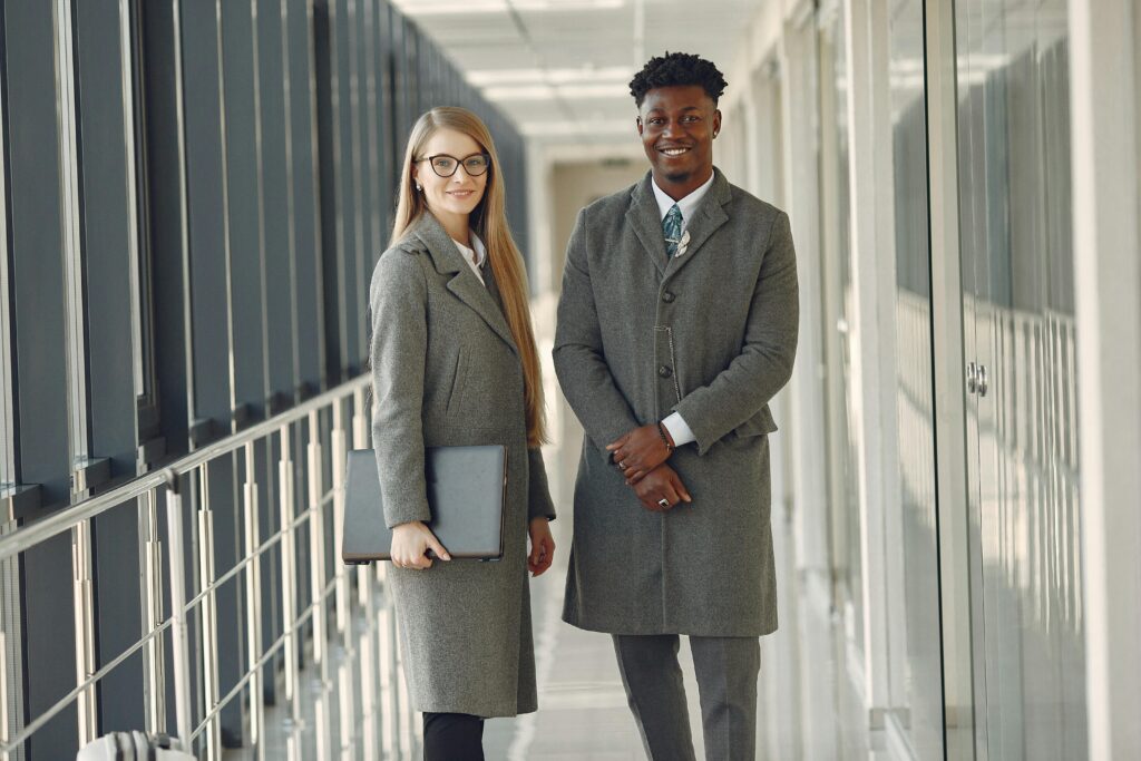 Business professionals standing in a modern office hallway, exuding confidence and style.