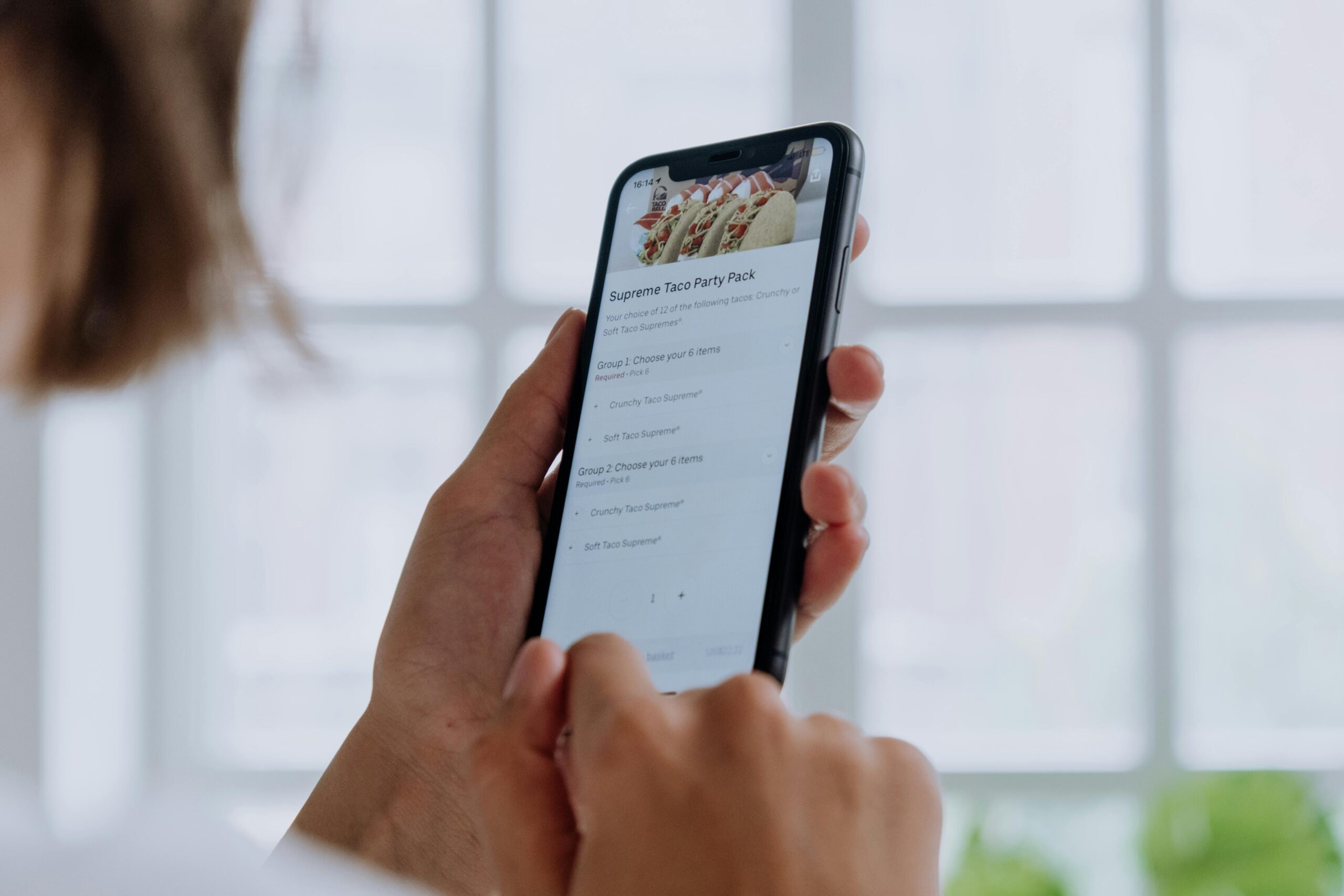 Close-up of hands using a smartphone to order food online through an app, showcasing modern technology.
