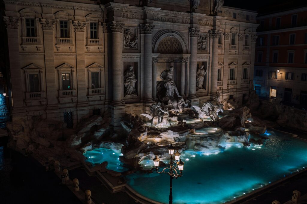 A stunning nighttime view of the illuminated Trevi Fountain, a famous landmark in Rome, Italy.