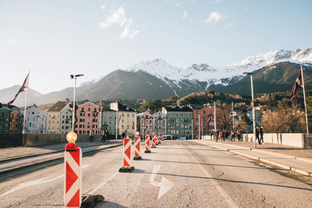 Charming street view of Innsbruck with colorful buildings and snow-capped mountains in the background.
