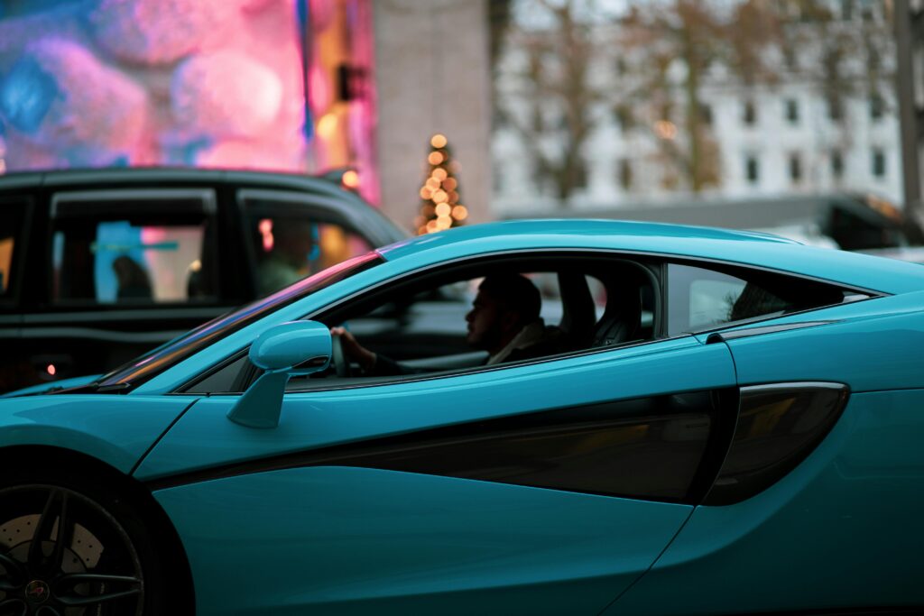 A blue supercar navigates the busy streets of London, showcasing luxury automotive design.