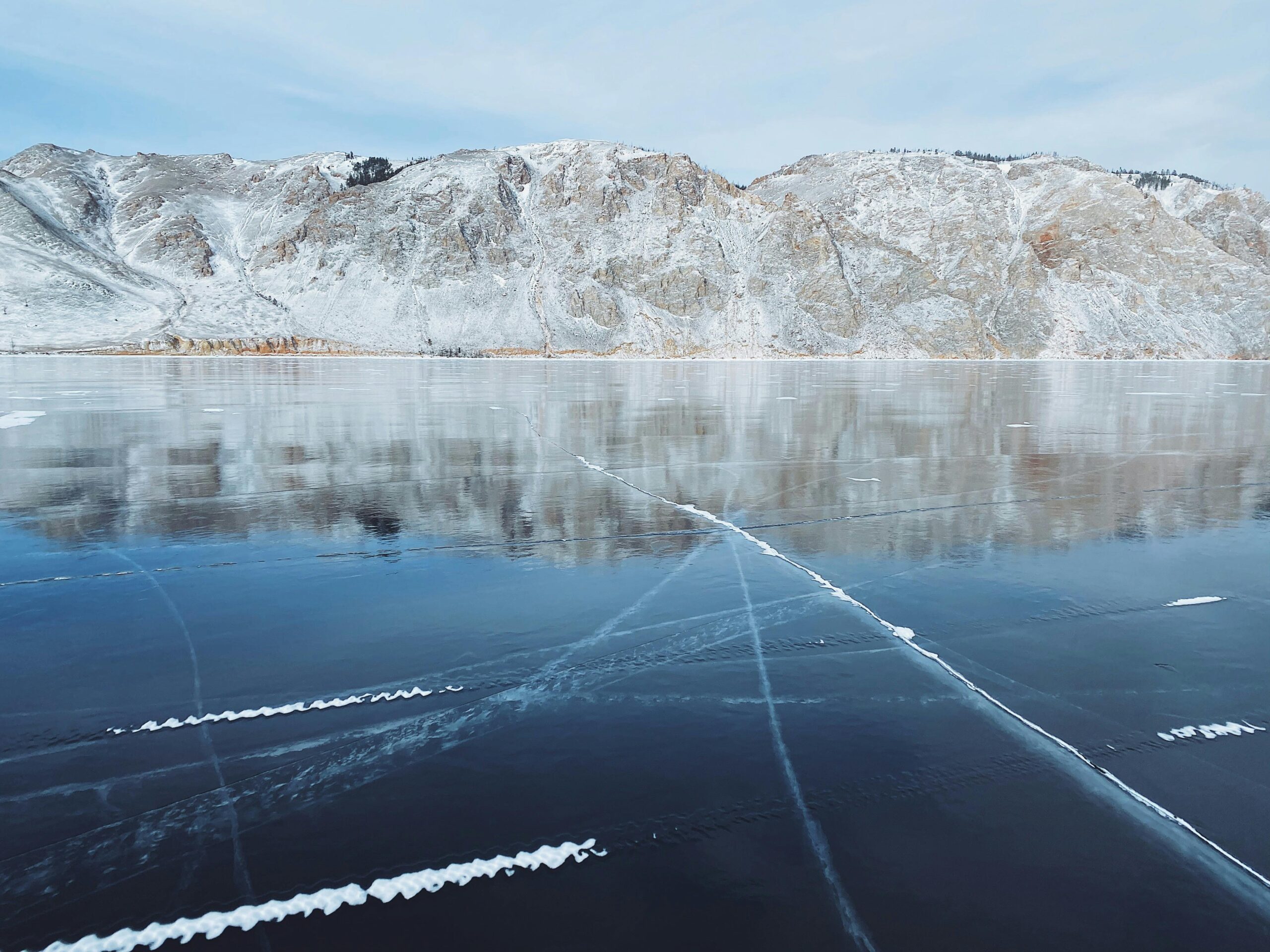 Pristine view of frozen Lake Baikal with snowy mountains in Russia's winter landscape.