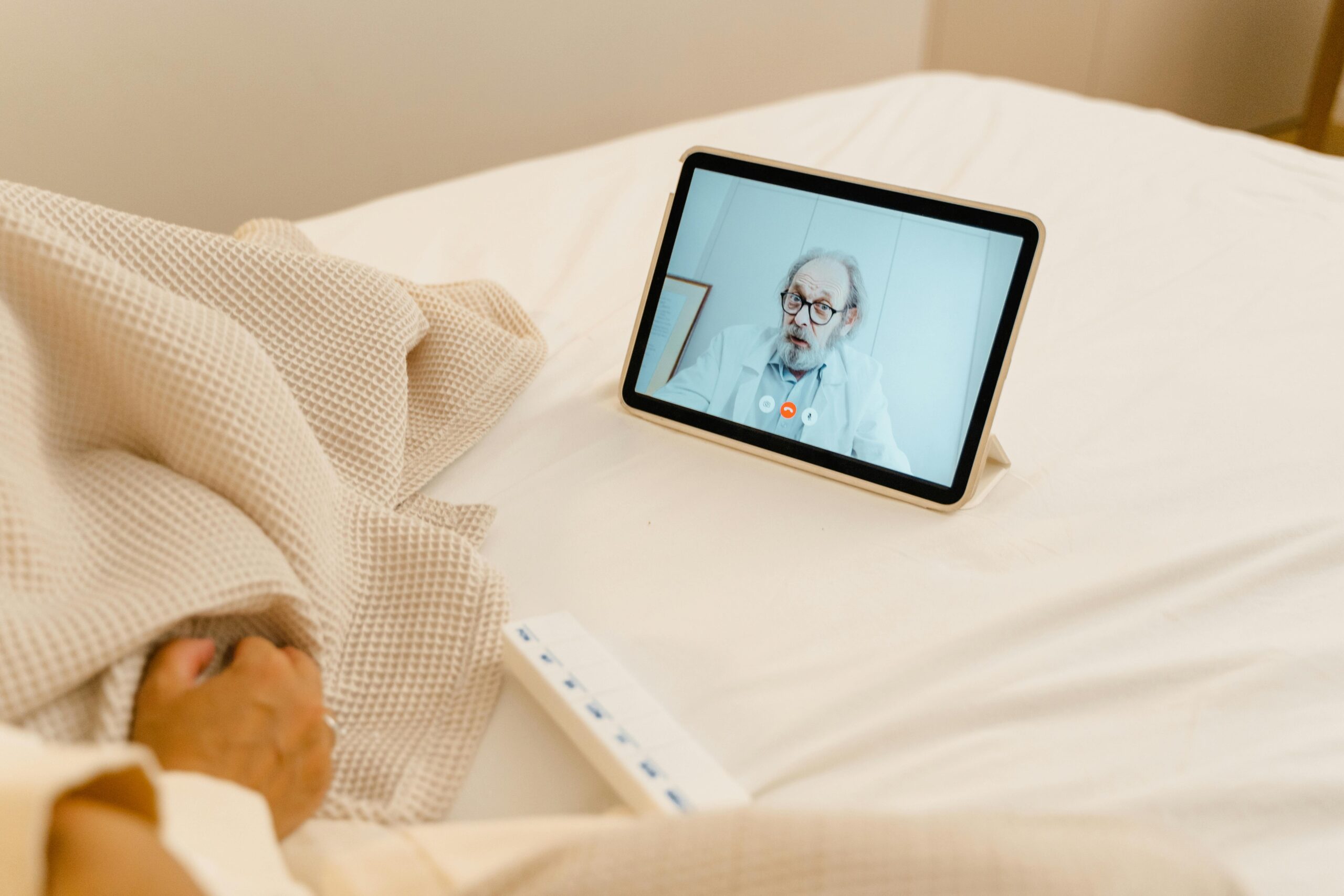 Patient in bed having a virtual consultation with a doctor via tablet.