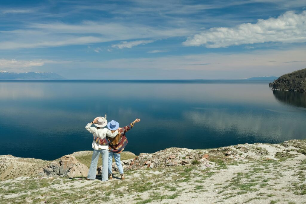 Two women enjoying a scenic view over Lake Baikal in summer, embracing adventure and nature.