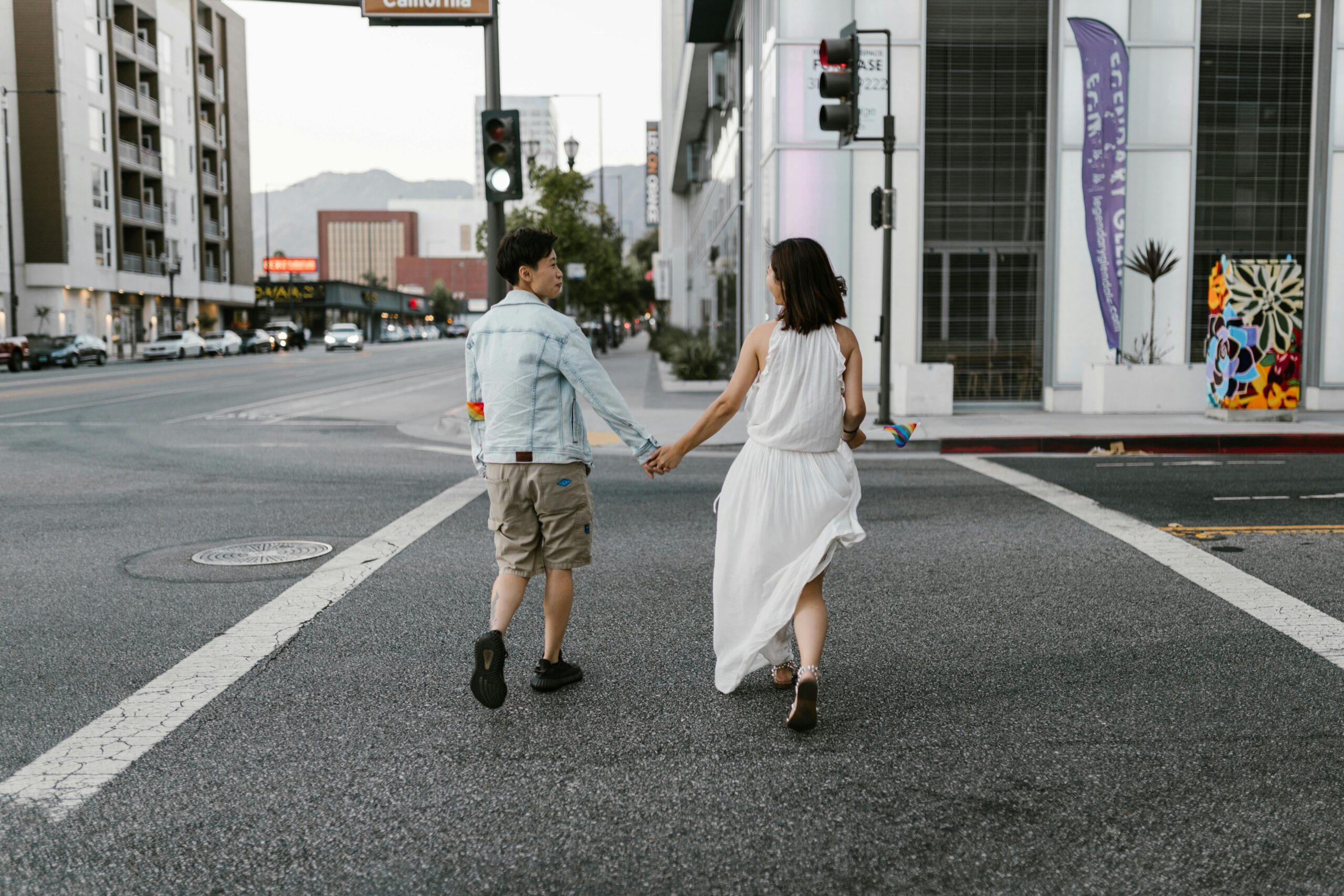 A couple holding hands and crossing the street in an urban setting, exuding a sense of freedom and connection.