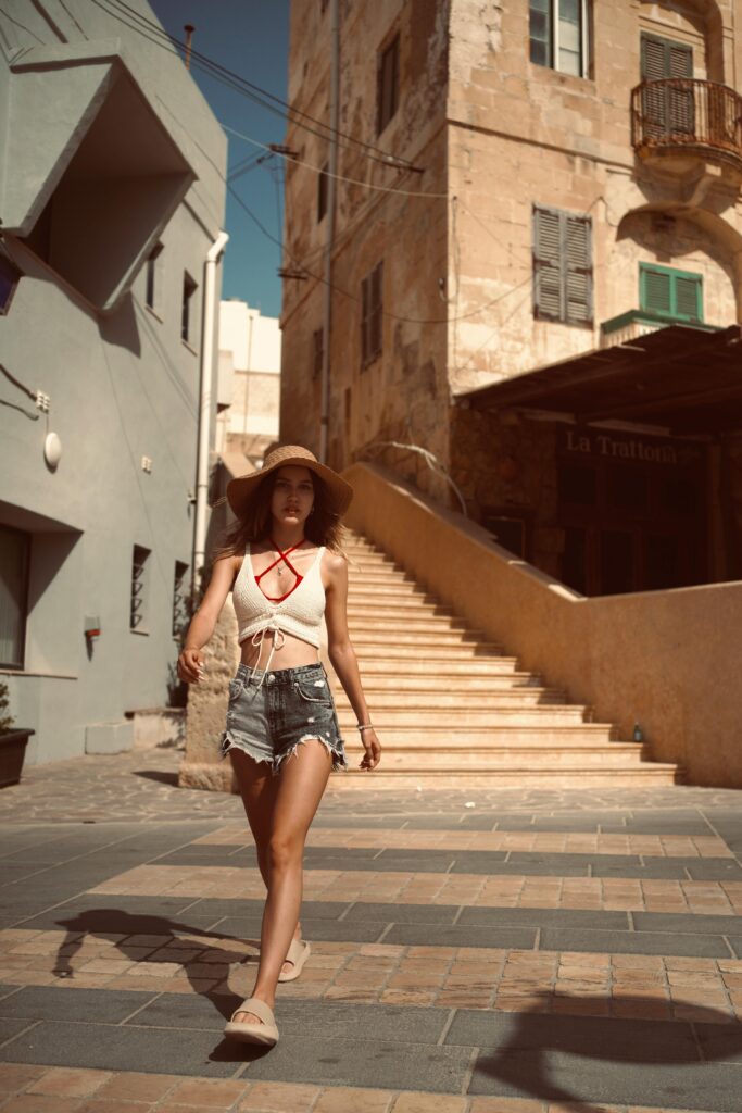 Woman in summer outfit walking through a sunlit European town with historic architecture.