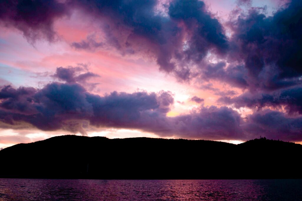 Breathtaking pink and purple sunset over mountains and water in Whitsundays, Australia.