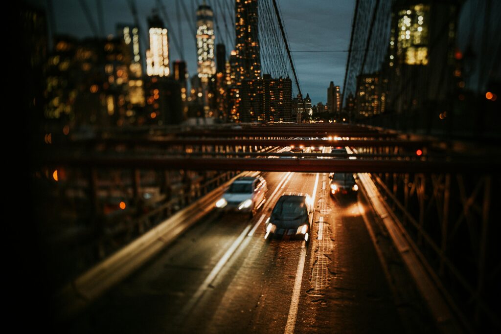 Dynamic night view of Brooklyn Bridge with cars and city skyline in New York City.