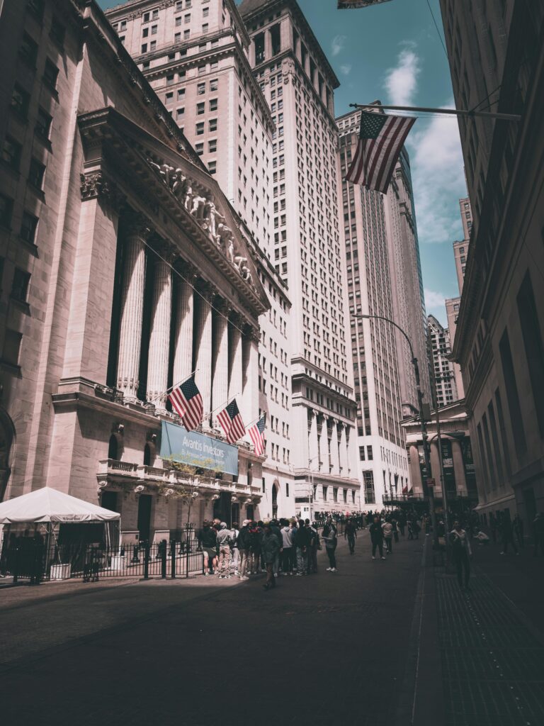 View of New York Stock Exchange on a busy day with American flags and skyscrapers.