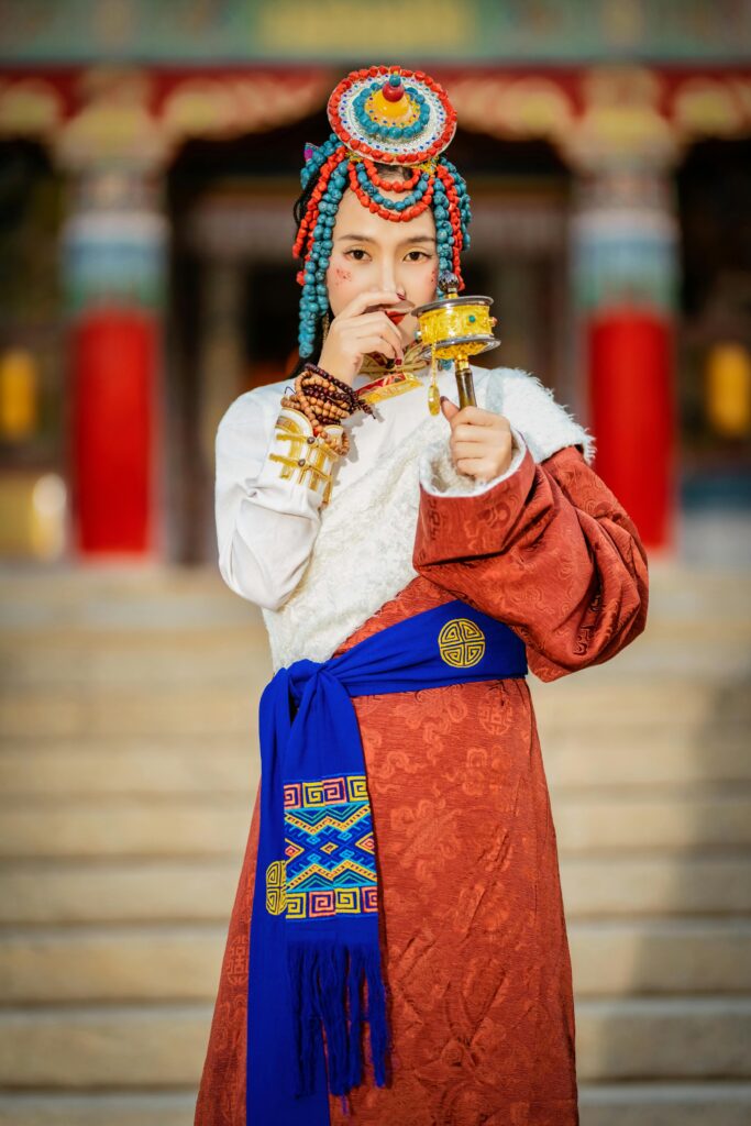 Portrait of a young woman in vibrant traditional Tibetan costume outdoors.
