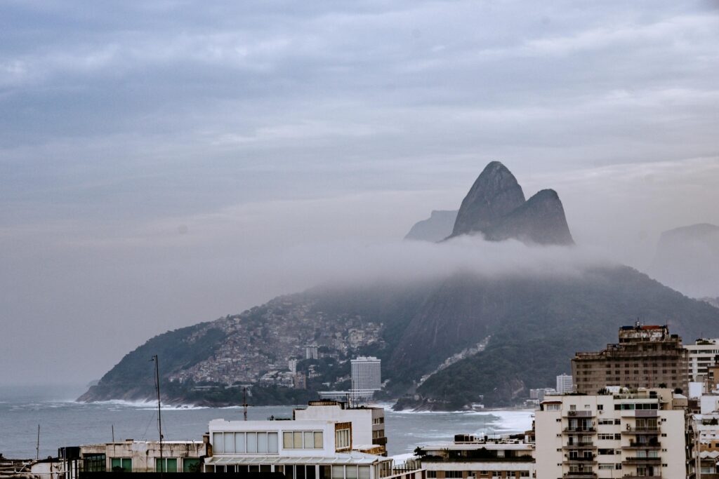 A foggy morning view of the iconic Two Brothers Hill in Rio de Janeiro, Brazil, showcasing modern architecture and coastline.