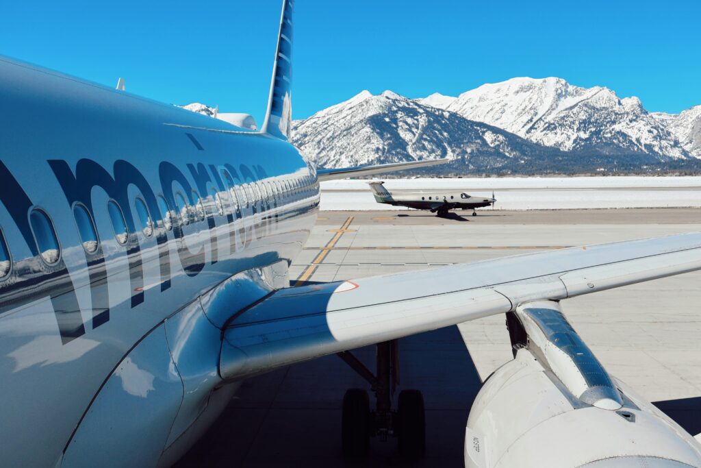 Airplanes parked at Jackson Hole Airport with snowy Teton mountains in the background.