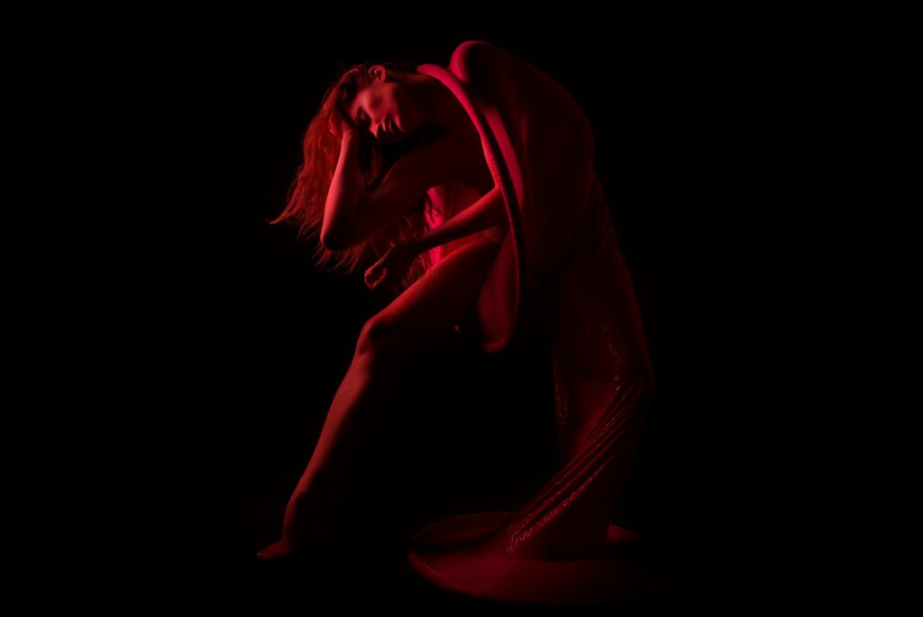 A captivating artistic nude image showcasing an elegant pose with dramatic lighting and shadows.