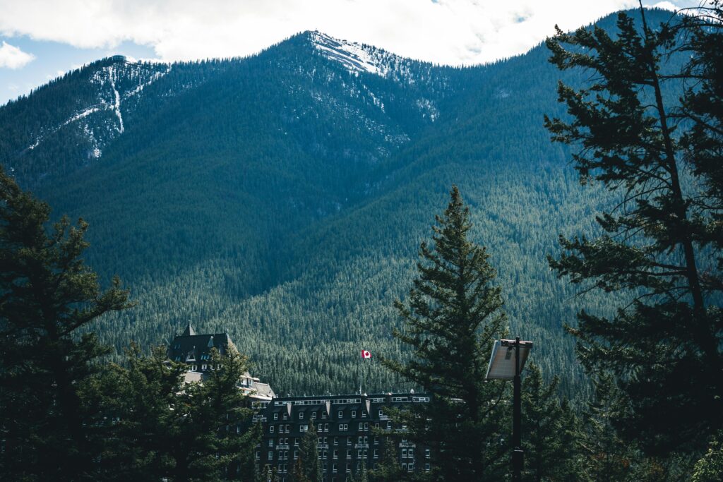 A beautiful view of Banff Springs Hotel nestled among the mountains and trees in Banff, Alberta.
