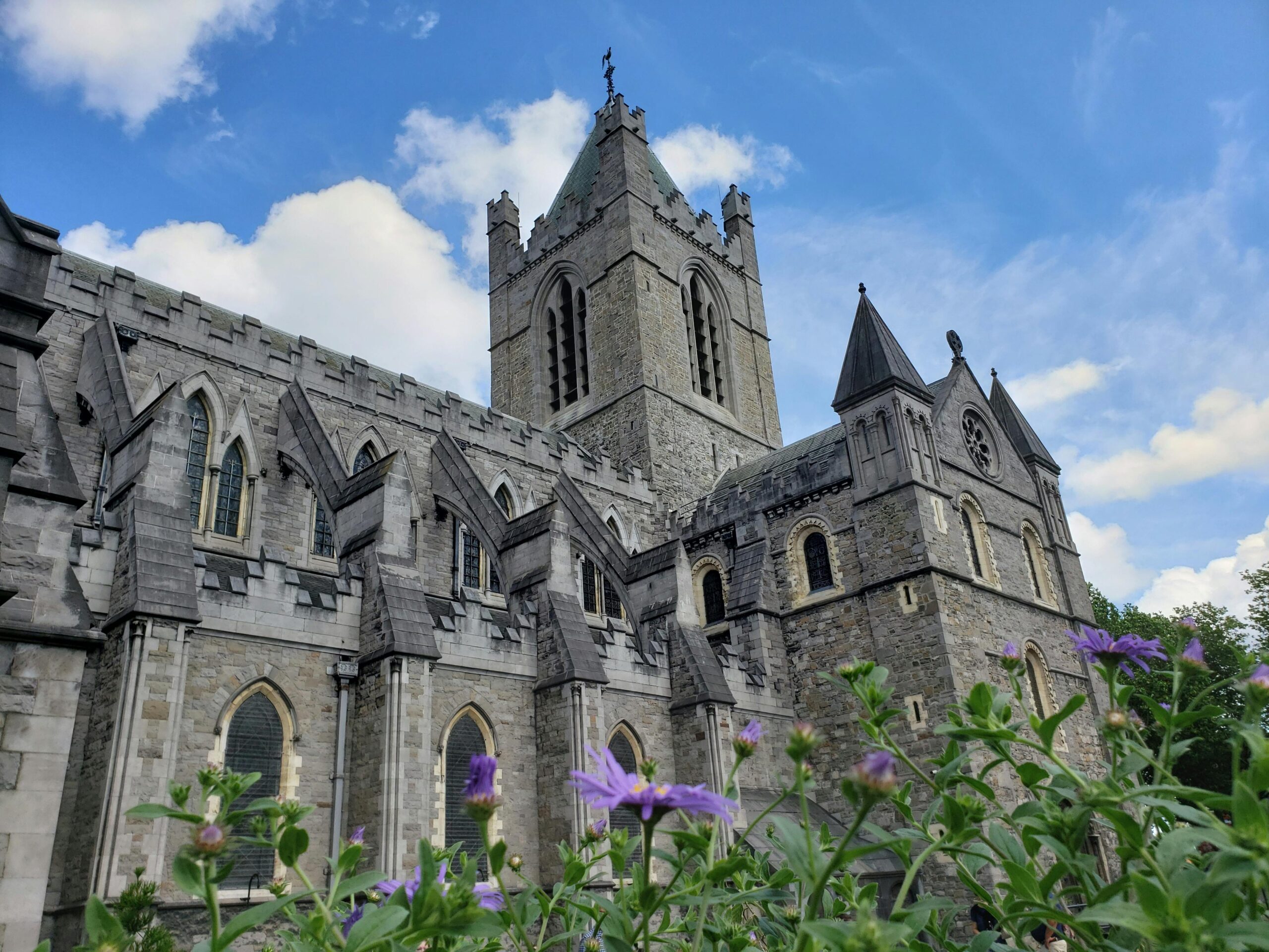 Beautiful view of a gothic cathedral in Dublin with blue sky and flowers.