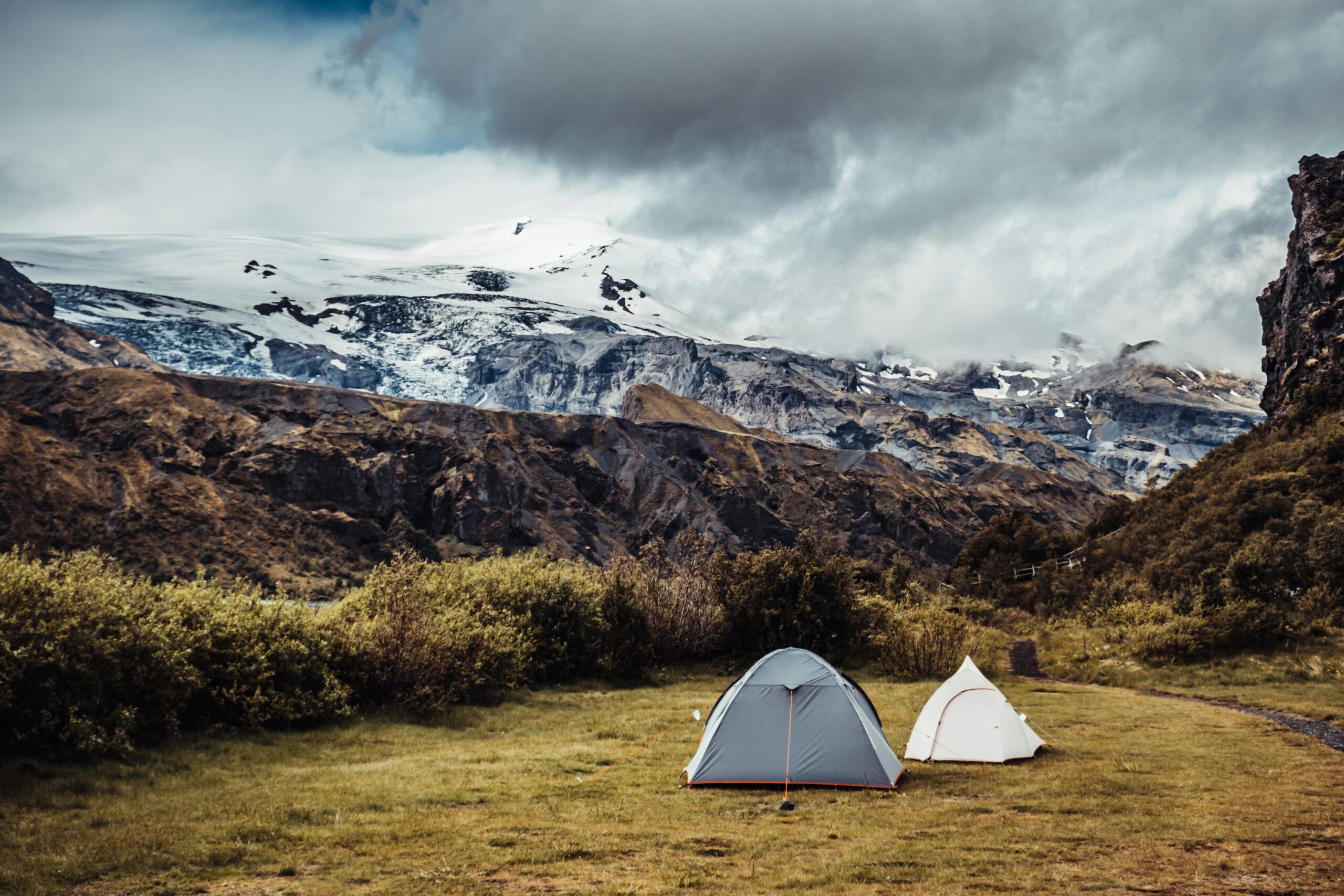 Two tents at a vibrant mountain campsite in Iceland with stunning glacier views.