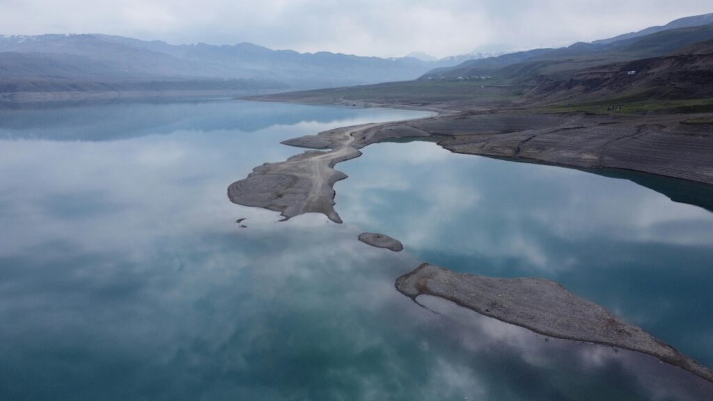 Captivating aerial view of a serene lake in Papan, Kyrgyzstan, reflecting the cloudy sky.