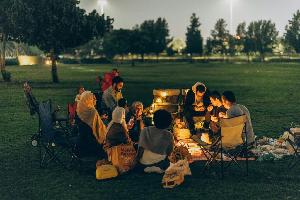 A cozy evening picnic in Abu Dhabi park with family and friends sharing food and warm moments.