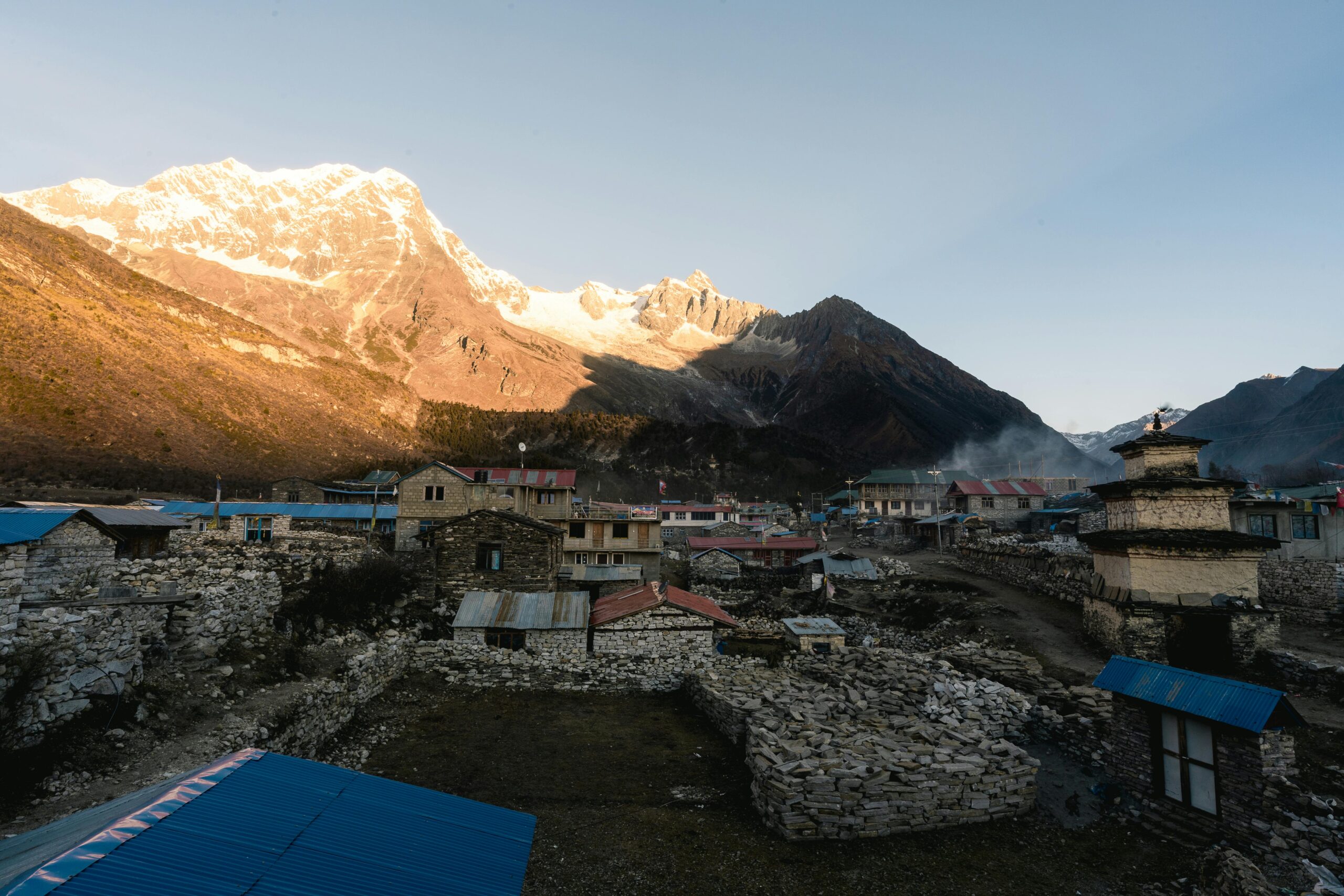 A serene Himalayan village with mountains at sunrise, showcasing rustic architecture in Nepal.