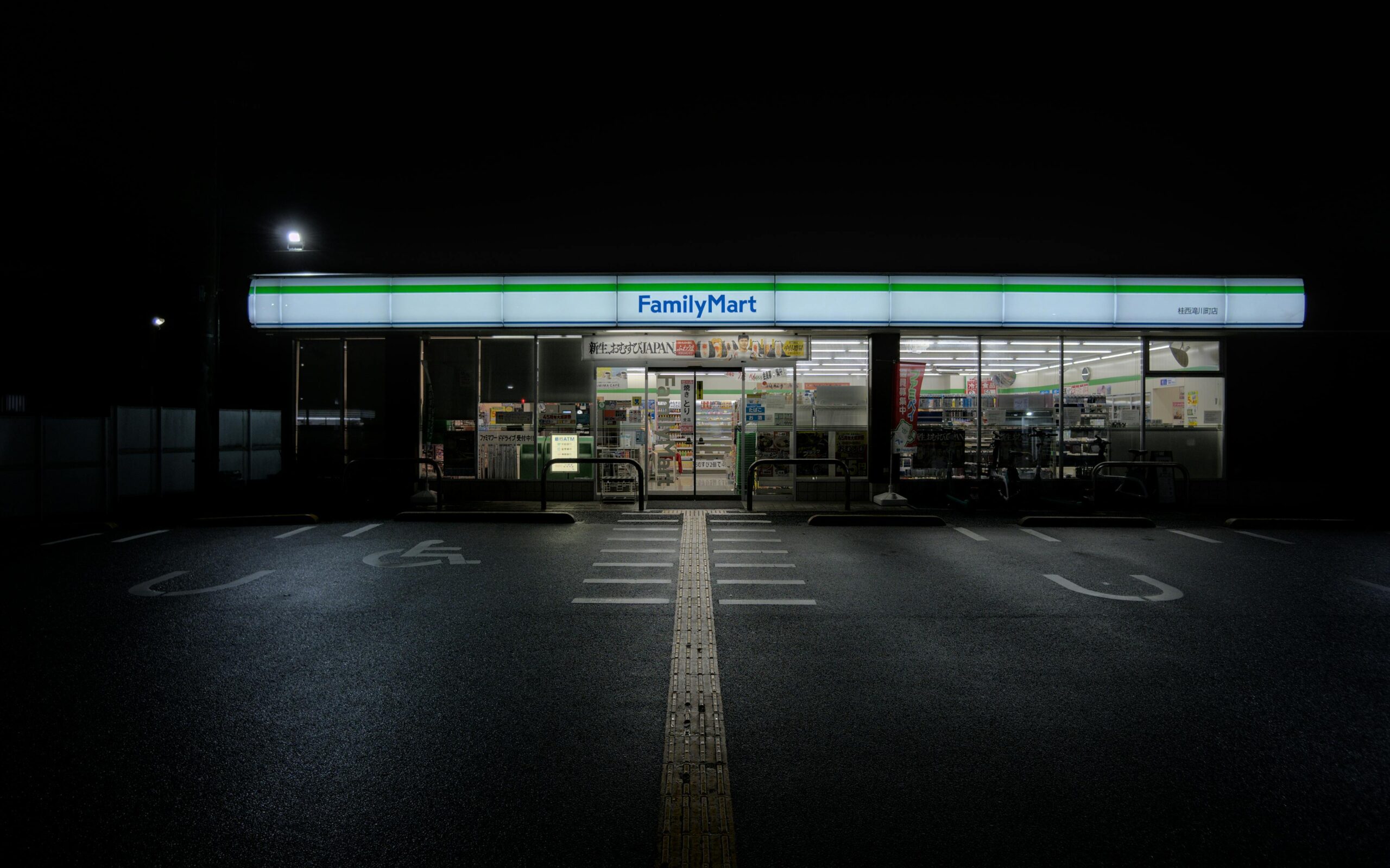 A serene nighttime view of an illuminated FamilyMart convenience store in Kyoto, Japan.