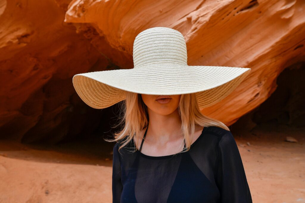 Fashionable woman in a sun hat near red sandstone on a sunny day in Mallorca, Spain.
