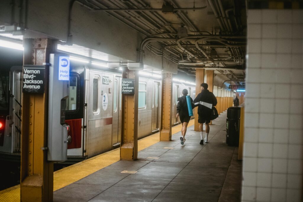 Two people walking on Vernon Blvd-Jackson Avenue subway platform in New York City.