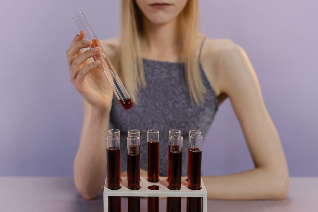 A woman in a lab handling red liquid in test tubes, showcasing scientific research.