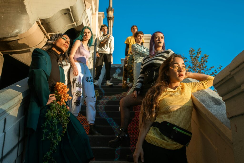 Group of diverse young adults posing confidently on a brightly decorated urban staircase.