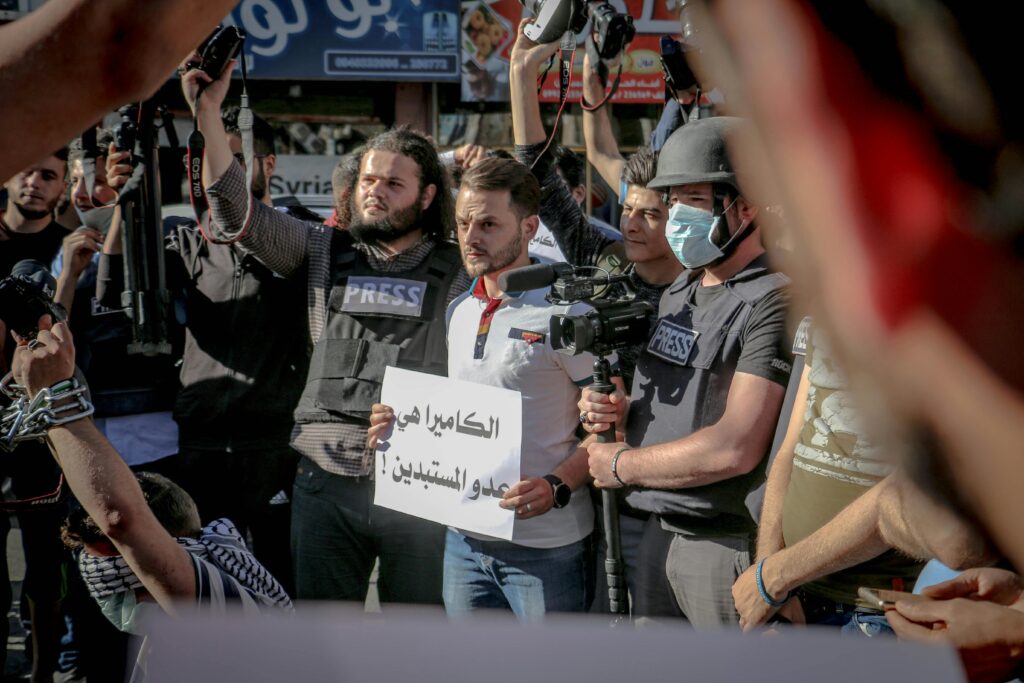 Group of ethnic journalists with placard with Arabic inscription and cameras at demonstration against policy