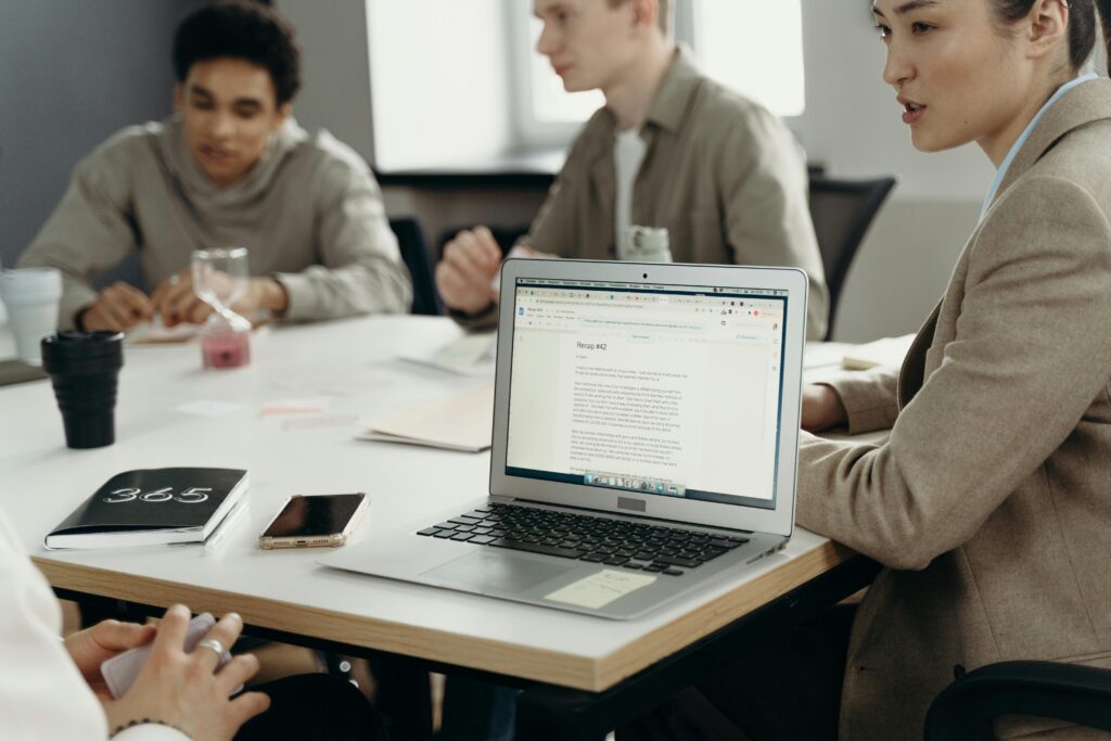 Diverse team engaging in a collaborative meeting around a table with laptops.