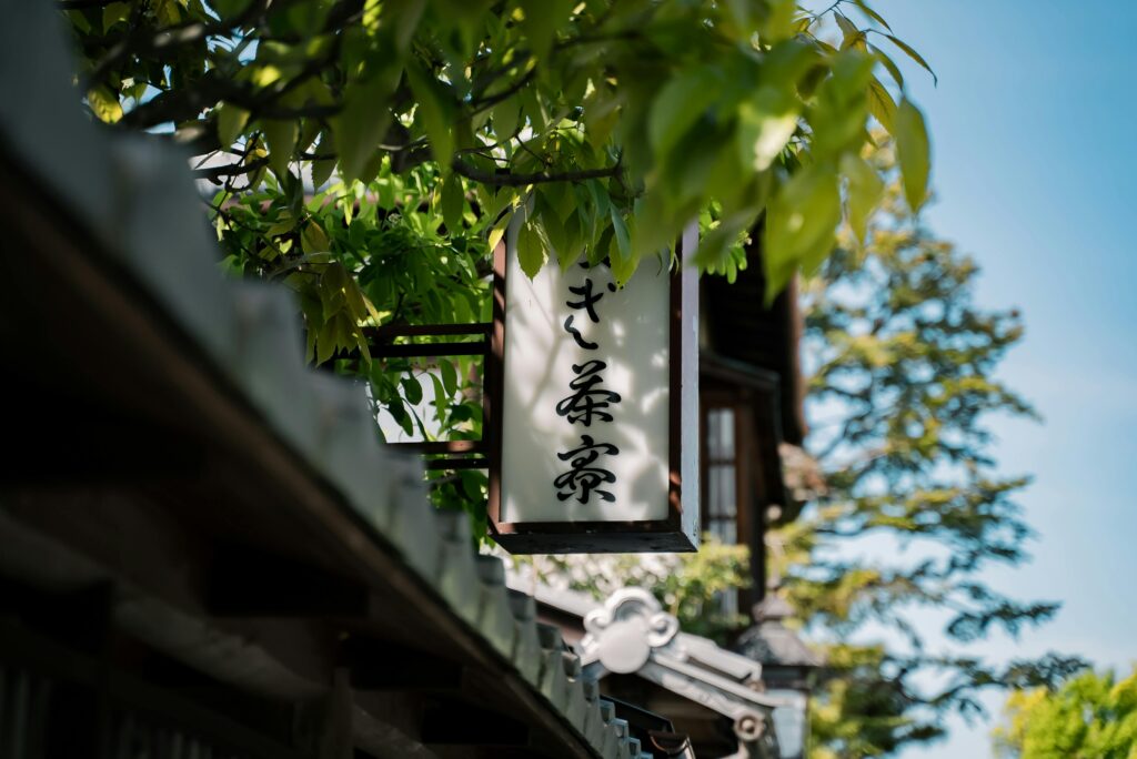 A traditional Japanese sign with calligraphy in Kyoto, Japan, surrounded by lush greenery.