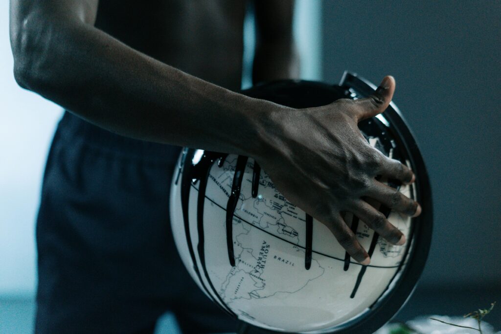 A hand holding a globe dripping with oil, symbolizing pollution and fossil fuels.