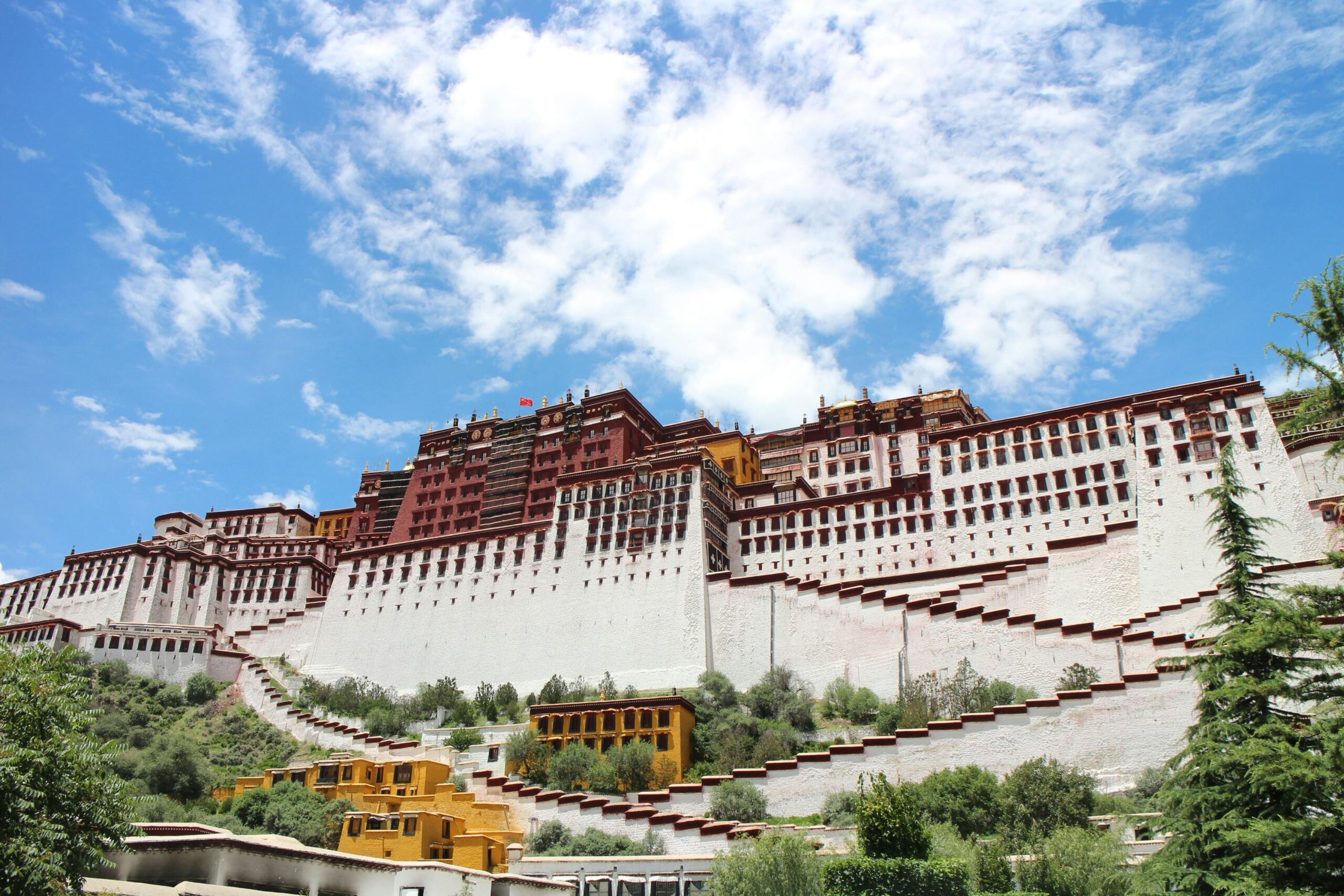 Stunning view of the Potala Palace in Lhasa, Tibet, with bright blue skies and white clouds.
