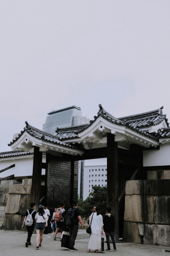 Visitors walking through the historic gate of Osaka Castle in Japan, showcasing traditional architecture.