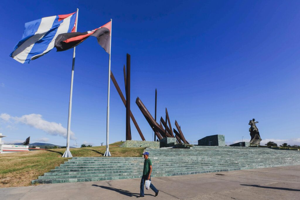 Wide view of Revolution Square in Santiago de Cuba, featuring flags and historical monument.