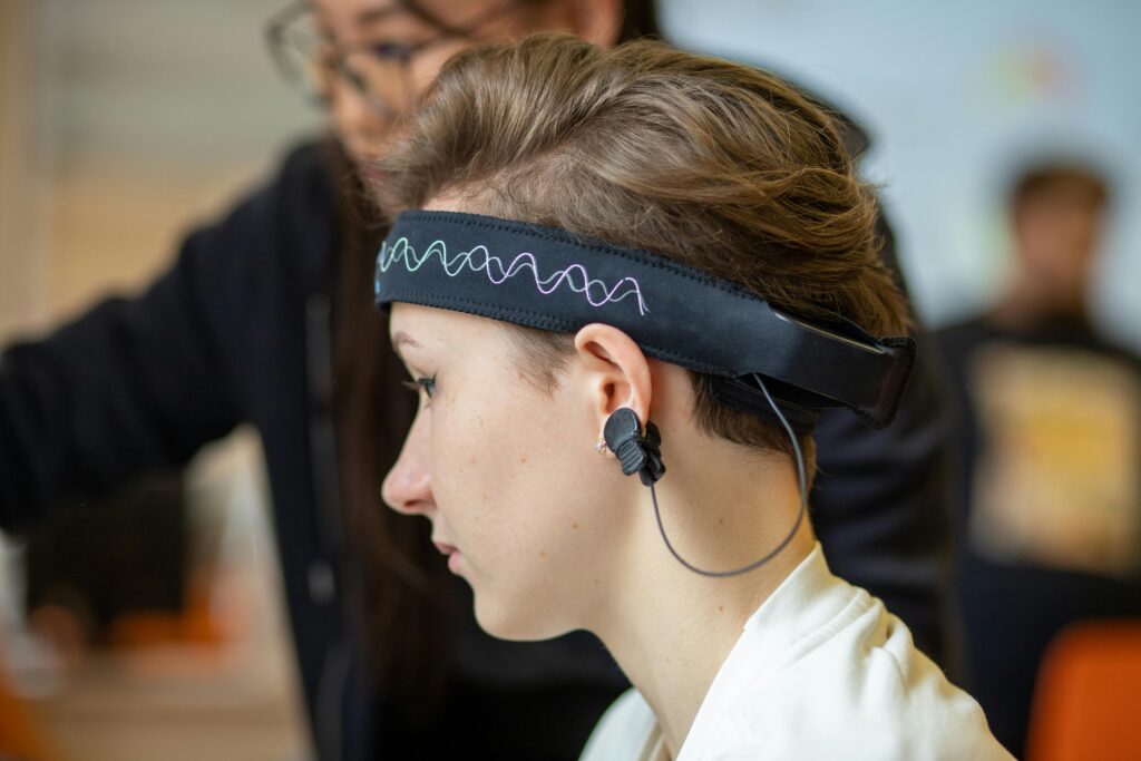 Close-up of a young woman wearing an EEG headband, showcasing modern technology indoors.