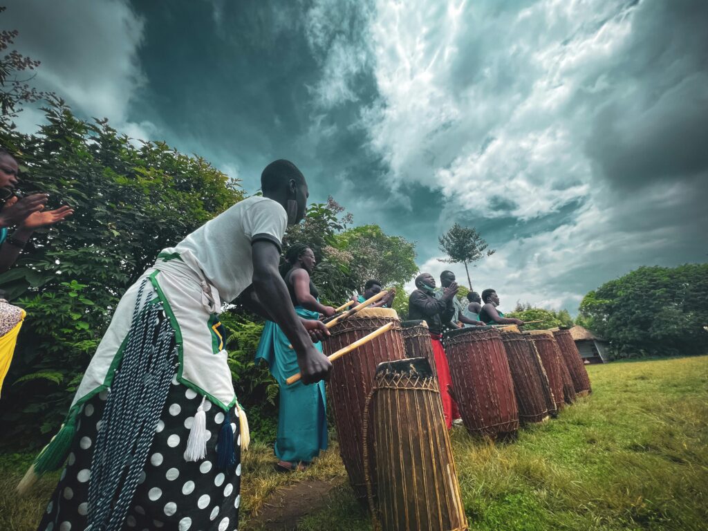 A group of people performing a traditional drumming ritual outdoors under a moody sky.