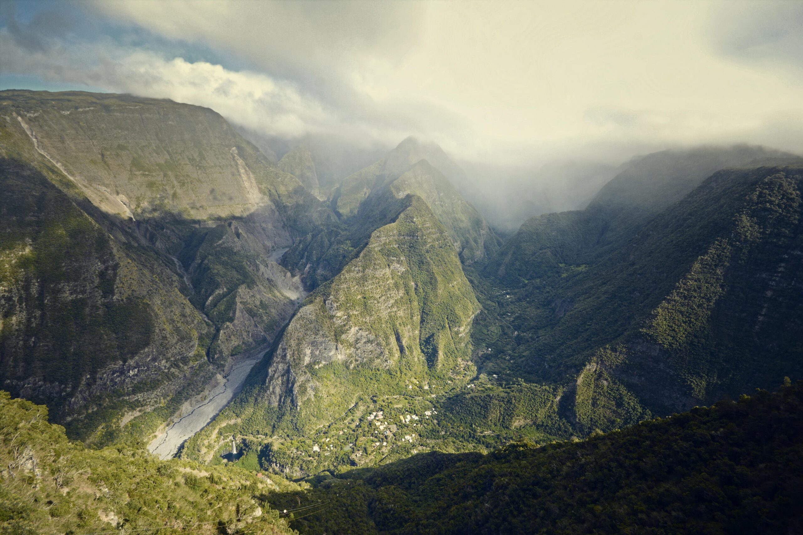 Breathtaking aerial view of lush green mountain valleys shrouded in clouds.