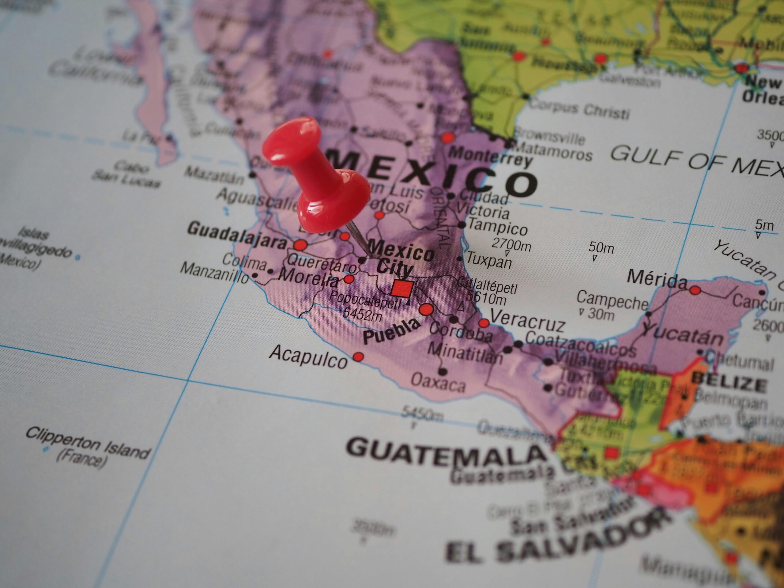 Detailed close-up of a map featuring Mexico with a red pushpin highlighting a location.