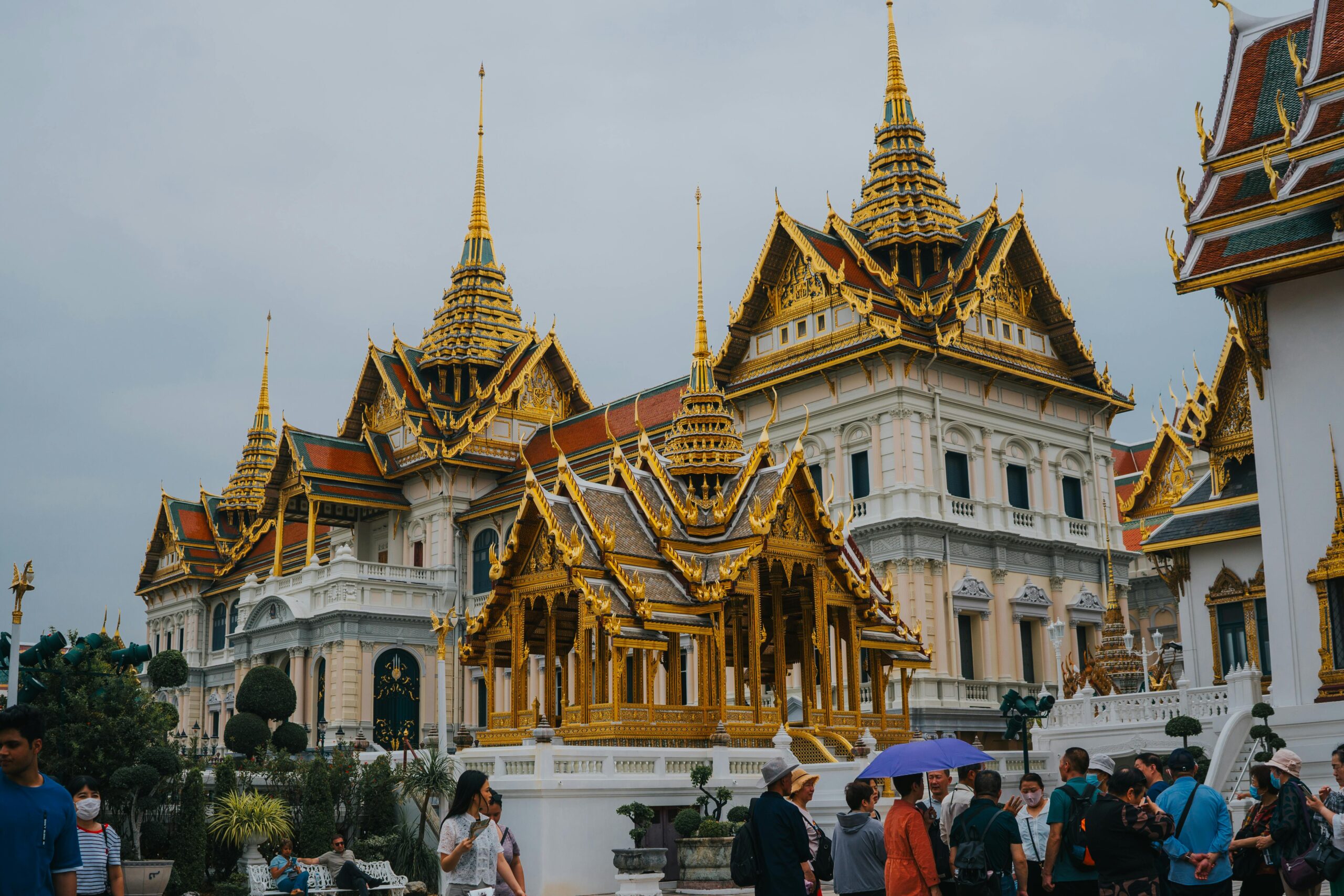 Tourists visit the majestic Grand Palace in Bangkok, Thailand, showcasing stunning traditional Thai architecture.
