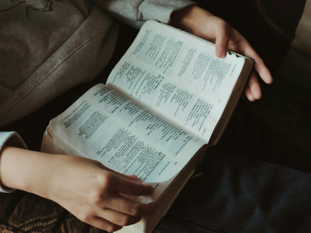 Hands immersed in reading a book with Asian text in a cozy setting.