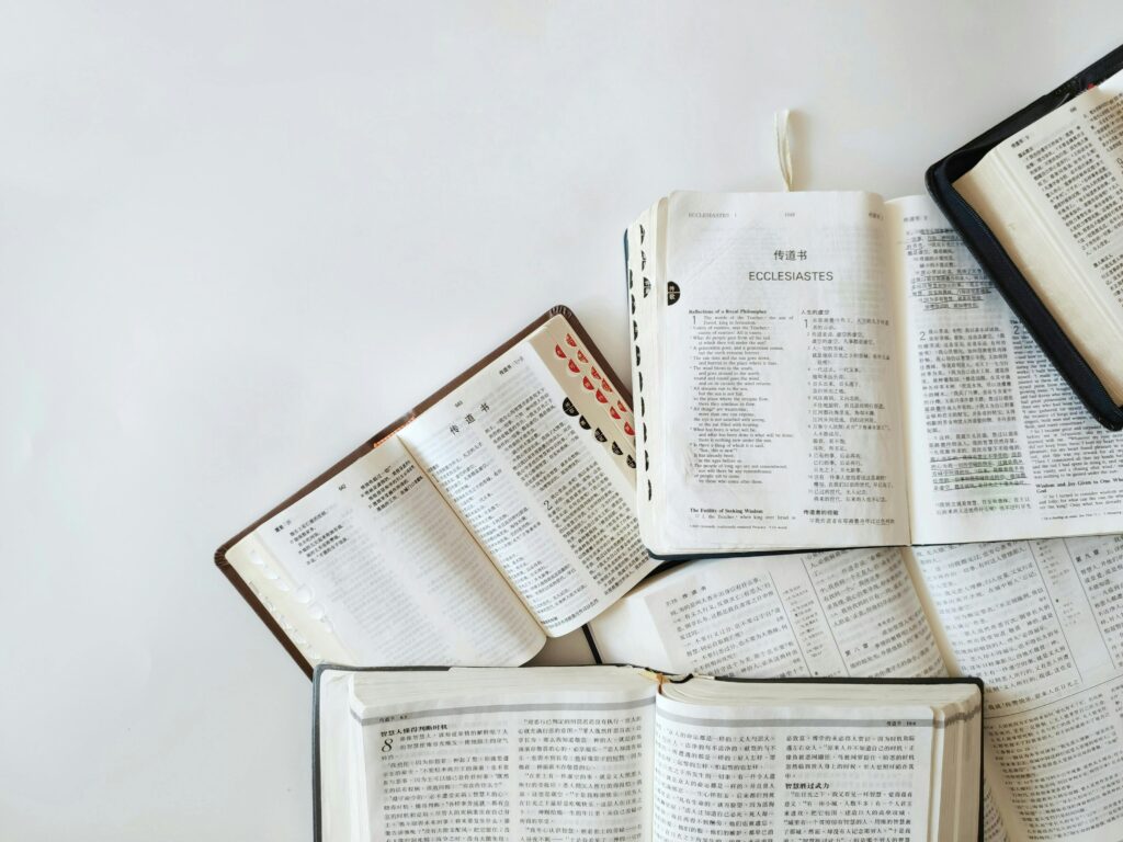 Multiple Bibles open on a white background showing text from Ecclesiastes in different languages.