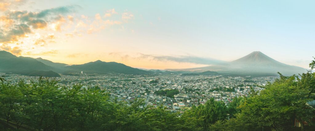 Panoramic view of Mount Fuji and Fujiyoshida cityscape at sunrise in Yamanashi, Japan.