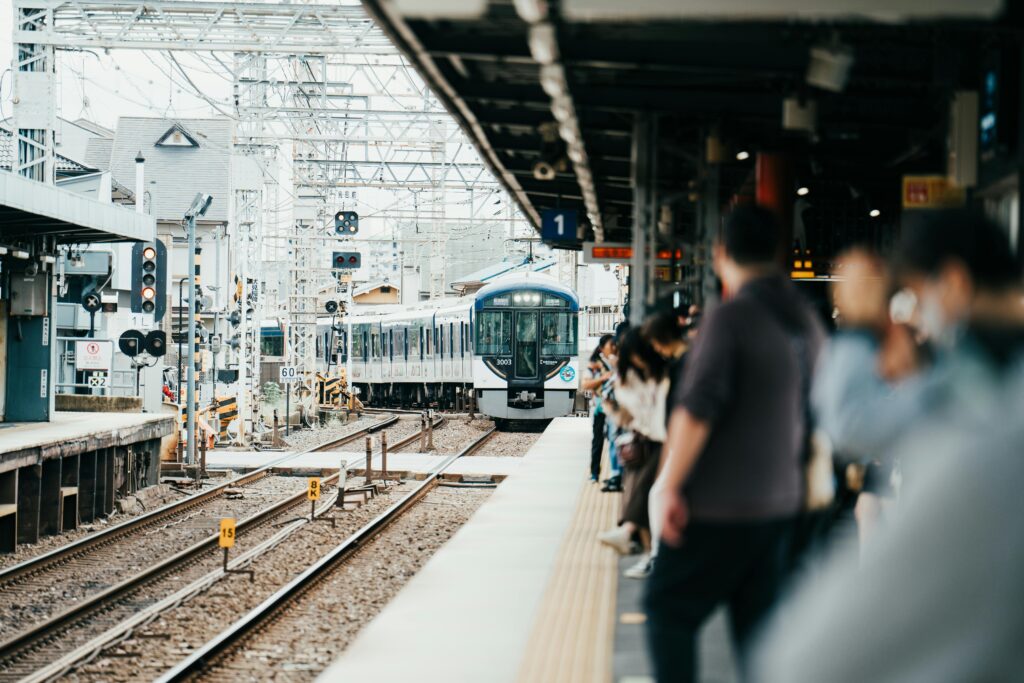 A train arriving at a bustling Japanese station filled with waiting passengers.
