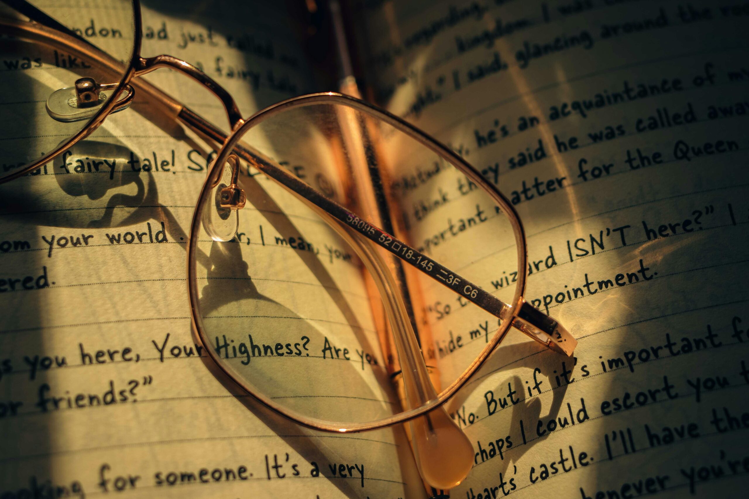 Vintage round spectacles rest on an open journal with handwritten notes.