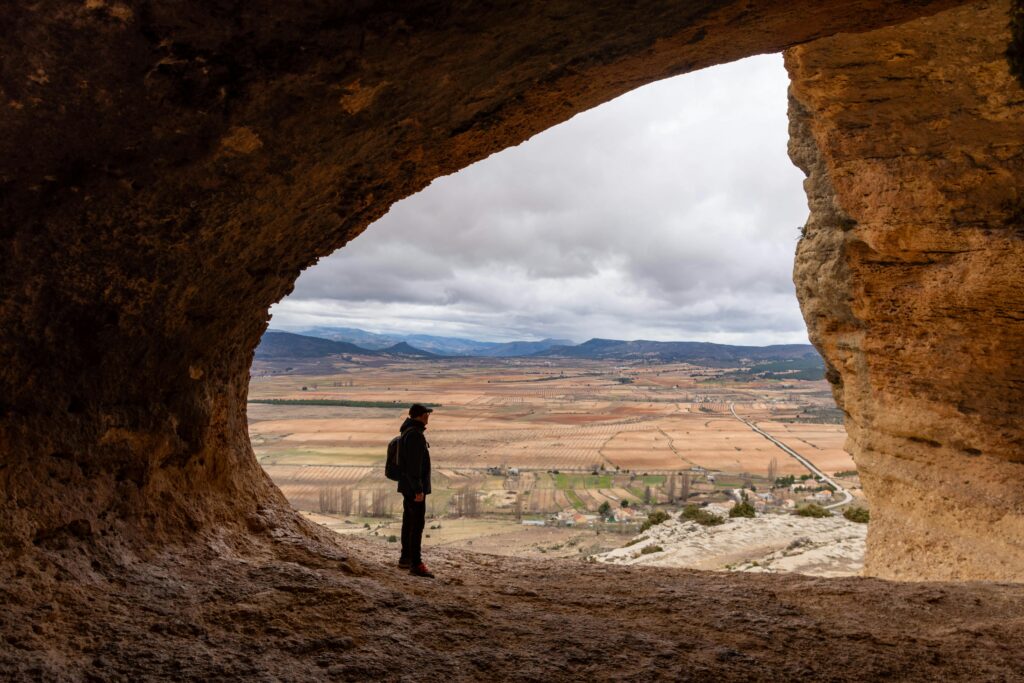 Traveler stands in a cave's entrance, overlooking stunning landscapes in Murcia, Spain.