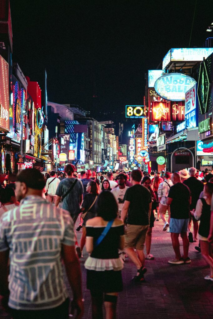 Bustling street with neon lights and crowds enjoying Bangkok's lively nightlife.