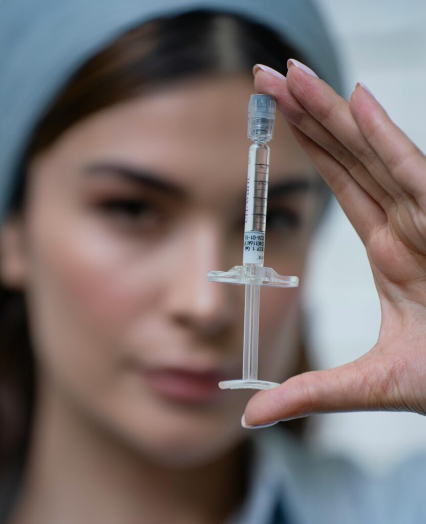 Close-up of a syringe held by a focused healthcare professional.
